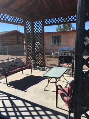 An outdoor patio area with a covered seating area, a grill, and a fenced enclosure. - King Suite w/ full kitchen, 2 twin Murphy beds & full bathroom  (Reserve)