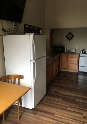 A compact kitchen with a refrigerator, microwave, toaster, and wooden cabinets. - King Suite w/ full kitchen, 2 twin Murphy beds & full bathroom  (Reserve)