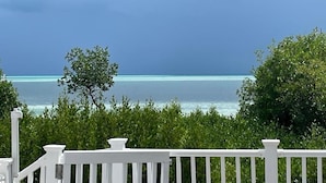 Vista di una spiaggia con un recinto bianco in primo piano e un cielo nuvoloso.
