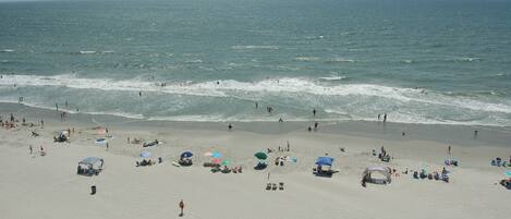 A beach with people, umbrellas, and beach chairs.