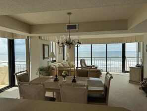 Ein geräumiger Essbereich mit großem Tisch und Stühlen, einer Chandelier und Blick aufs Meer.