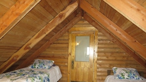 A small attic bedroom with two single beds, wooden walls, and a sloped ceiling. - Bluebird cabin in Stanley, Idaho (Stanley)