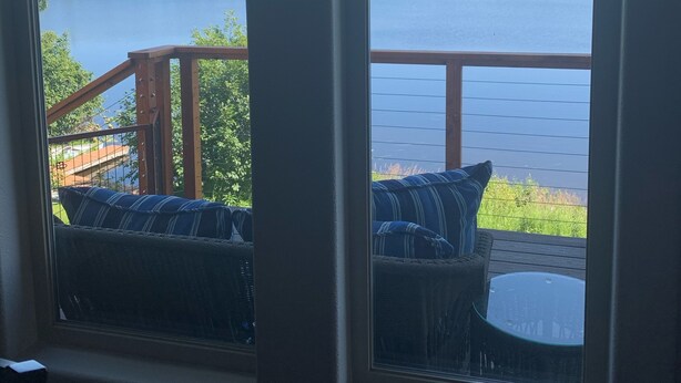 Ein Zimmer mit zwei Fenstern mit Blick auf einen See und Wald.