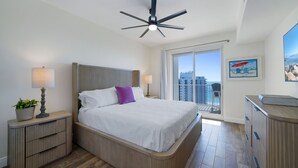 Habitación de hotel moderna con una cama grande, ventilador de techo, vistas a la ciudad y un balcón.
