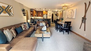 A living room with a sofa, coffee table, and dining area with chairs and a table. - Luxury Condo w/ FREE WiFi, Parking, Heated Pool, Hot Tubs, Skier Shuttles (Avon)