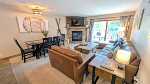 A living room with a fireplace, a dining area, and a sofa. - Luxury Condo w/ FREE WiFi, Parking, Heated Pool, Hot Tubs, Skier Shuttles (Avon)