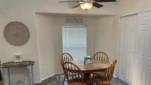 A dining area with a round wooden table and four chairs, a wall clock, and a ceiling fan. - The Cottage @ The Pleasant Street Suites in downtown Prescott (Prescott)