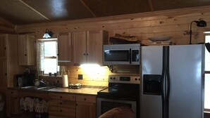 Cocina de cabaña de madera con refrigerador, microondas, horno y pileta.