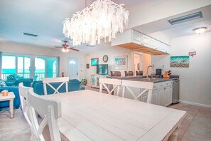 A spacious living area with a dining table, blue sofa, and a kitchen with white cabinets.
