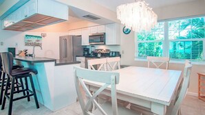 A kitchen with a dining area, a refrigerator, a microwave, a sink, and a chandelier.