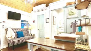 Cocina compacta con techo de madera, sofá a cuadros y una zona de bar con taburetes.