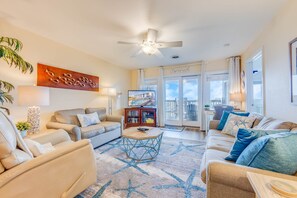 Relax in a spacious living room with a large flat-screen TV, comfortable seating area, and sliding glass door leading to a balcony.