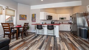 Una cucina moderna con mobili bianchi, un frigorifero in acciaio inossidabile e un pavimento in legno.