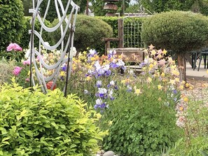 Een tuin met verschillende bloemen en een metalen sculptuur.
