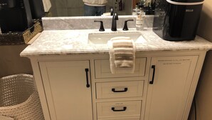 A bathroom with a white vanity, a sink, and a towel hanging on the countertop. - Tranquil East Wing Suite Redlands Grand Junction, Colorado (Grand Junction)
