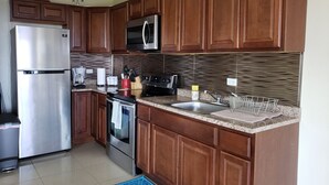 A kitchen with wooden cabinets, stainless steel appliances, a microwave, a toaster, and a sink.
