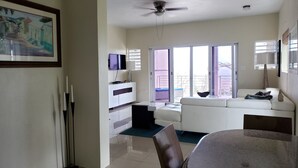 A spacious living room with a white sofa, a dining table, and a ceiling fan.