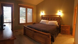 Een slaapkamer met een houten bed, twee bedlampen, een nachtkastje en een bureau met een stoel.