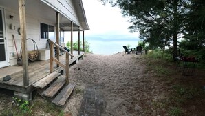 A wooden deck leading to a sandy beach area with outdoor furniture and a view of the water. - Access to the best white sand beach in the Keweenaw! (Gay)
