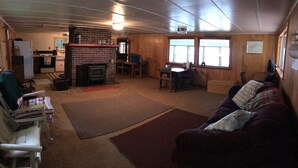 A cozy living room with a fireplace, a dining area, and a couch. - Access to the best white sand beach in the Keweenaw! (Gay)