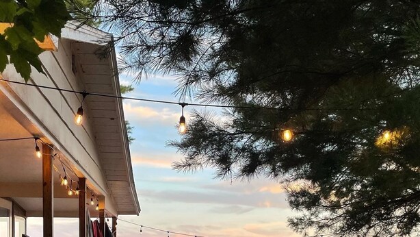 A wooden deck leading to a beach with a chair and a bench, overlooking the ocean. - Access to the best white sand beach in the Keweenaw! (Gay)
