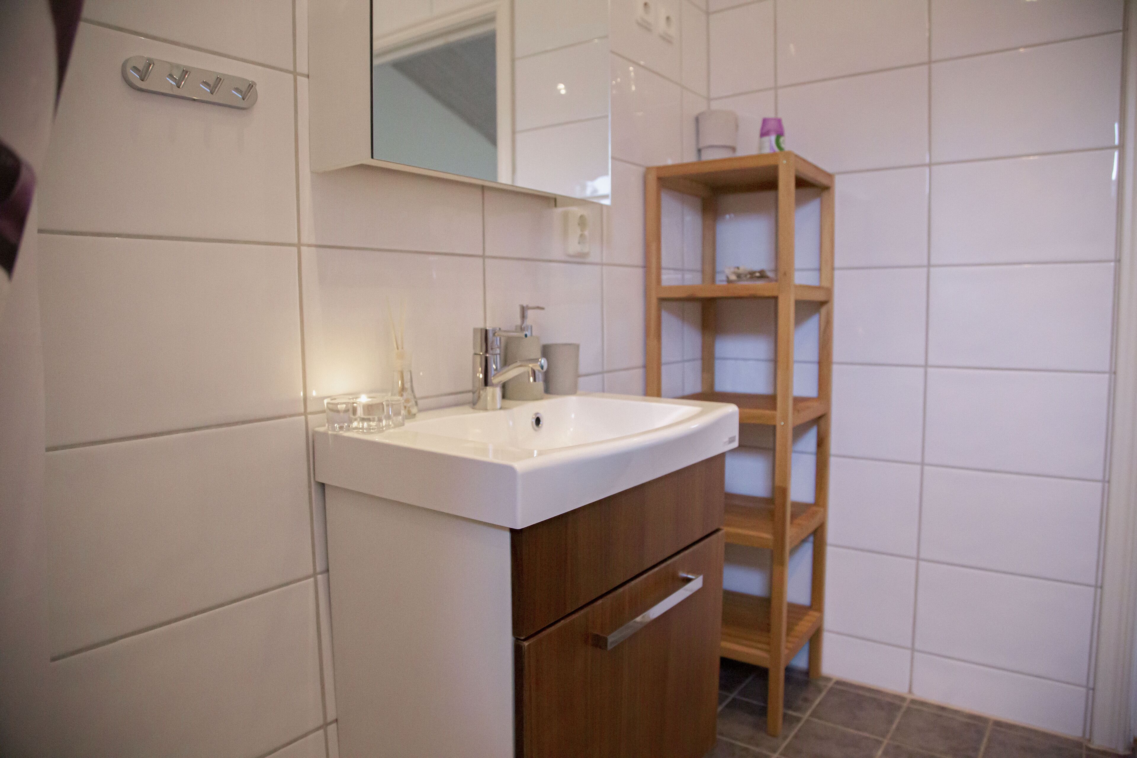 A bathroom with a white sink, wooden cabinet, and a mirror above the sink.
