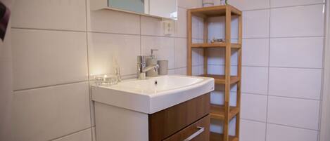 A bathroom with a white sink, wooden cabinet, and a mirror above the sink.