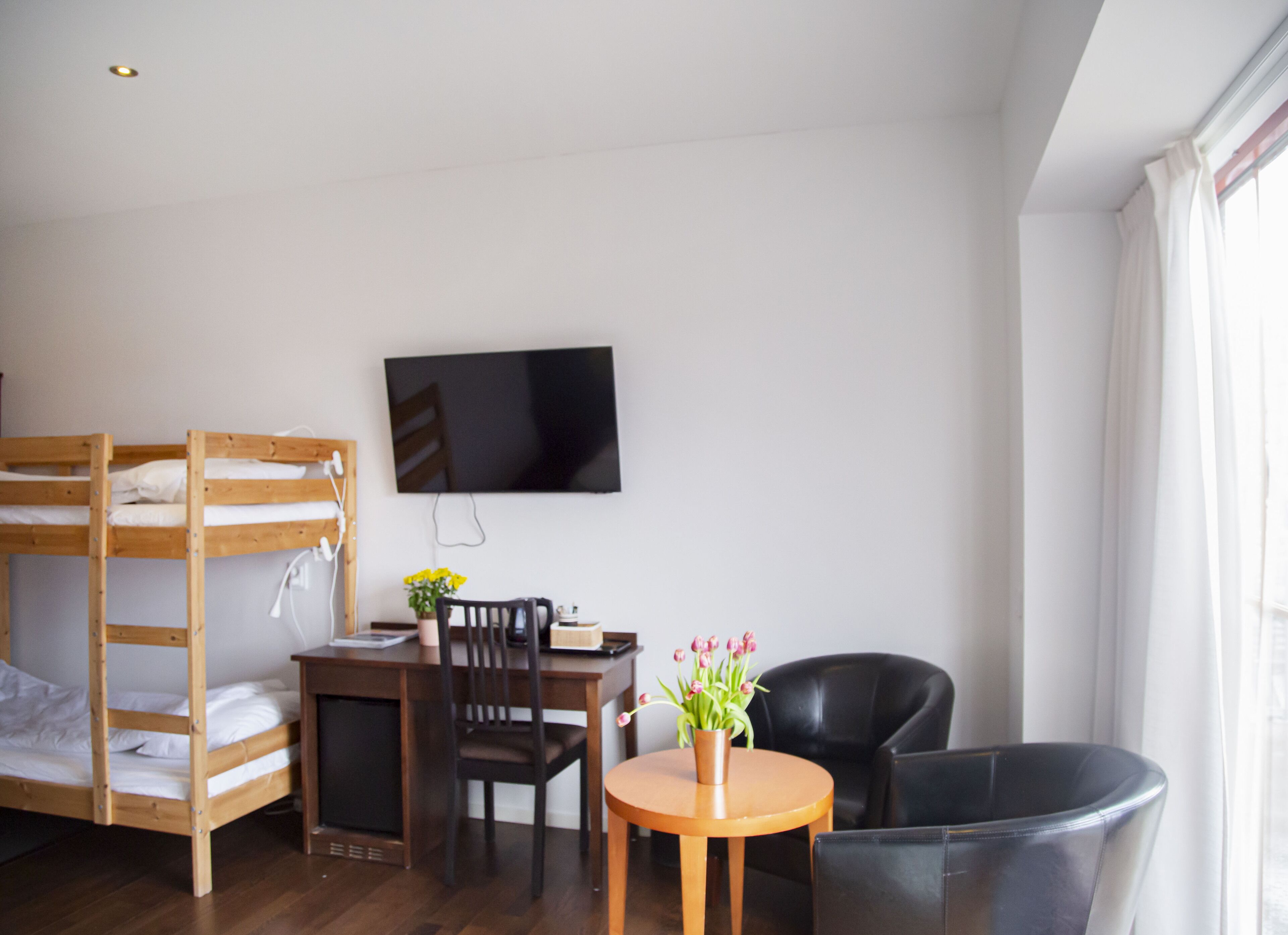Une chambre avec des lits superposés, un bureau, une chaise, une télévision et une fenêtre.