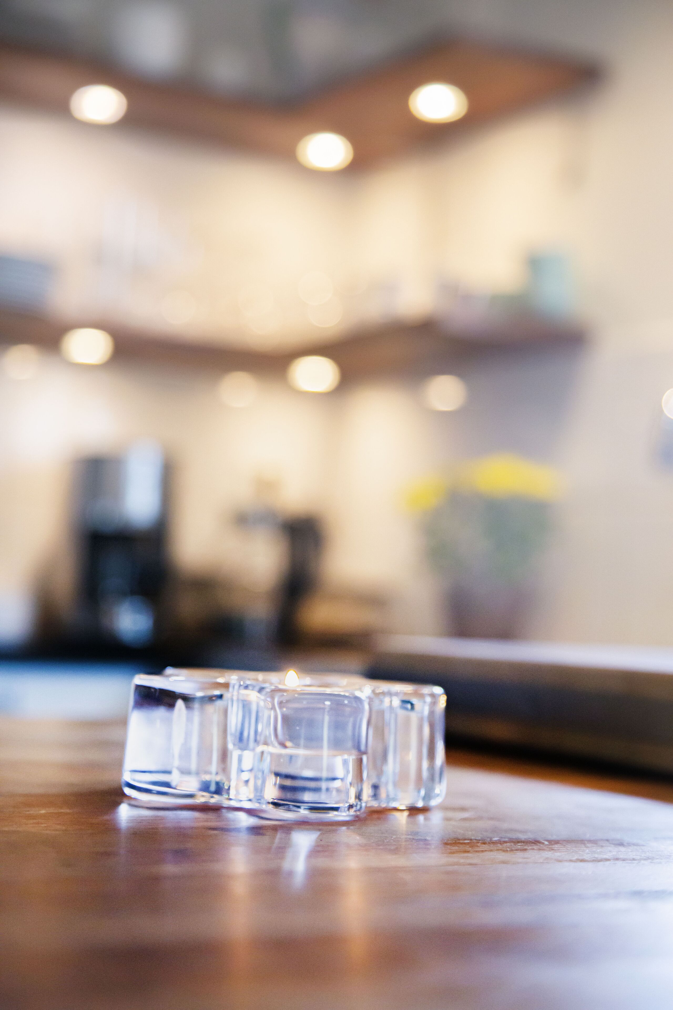 A blurred indoor setting with a wooden table and a glass object.