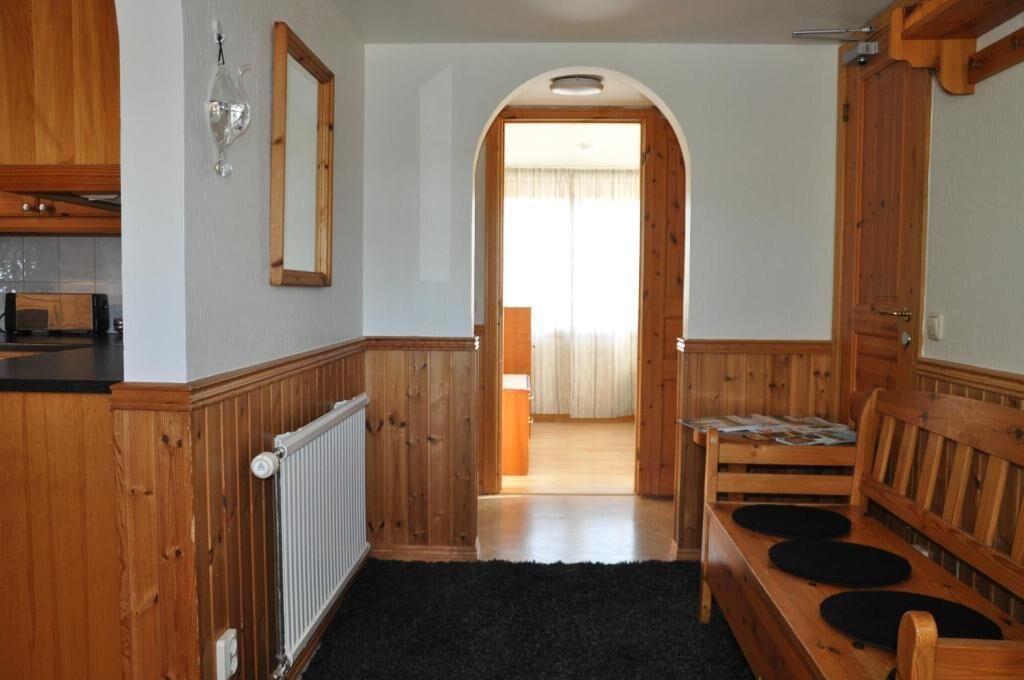 Un interior de madera con una zona de cocina, un banco y un acceso a otra habitación.