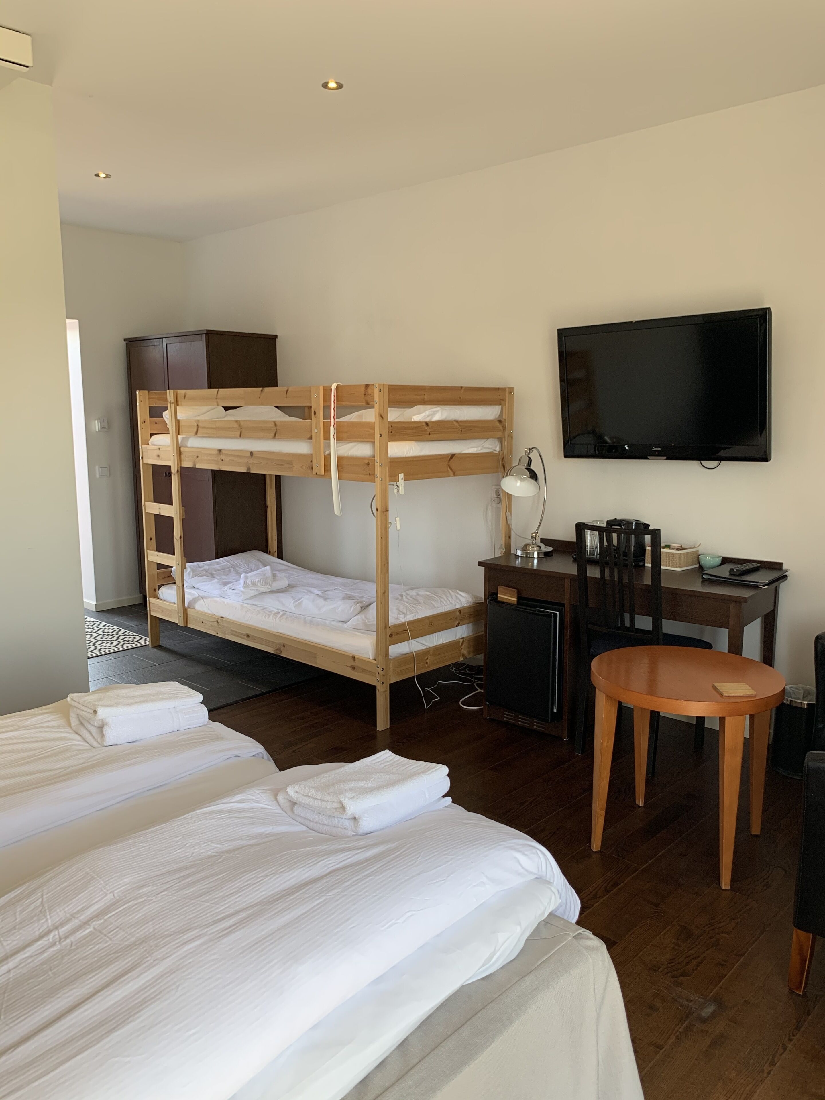 Habitació d'hotel amb un llit superposat, un escriptori amb una cadira, una televisió i una taula petita.