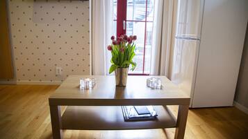 A wooden table with a vase of flowers and two glasses on it.