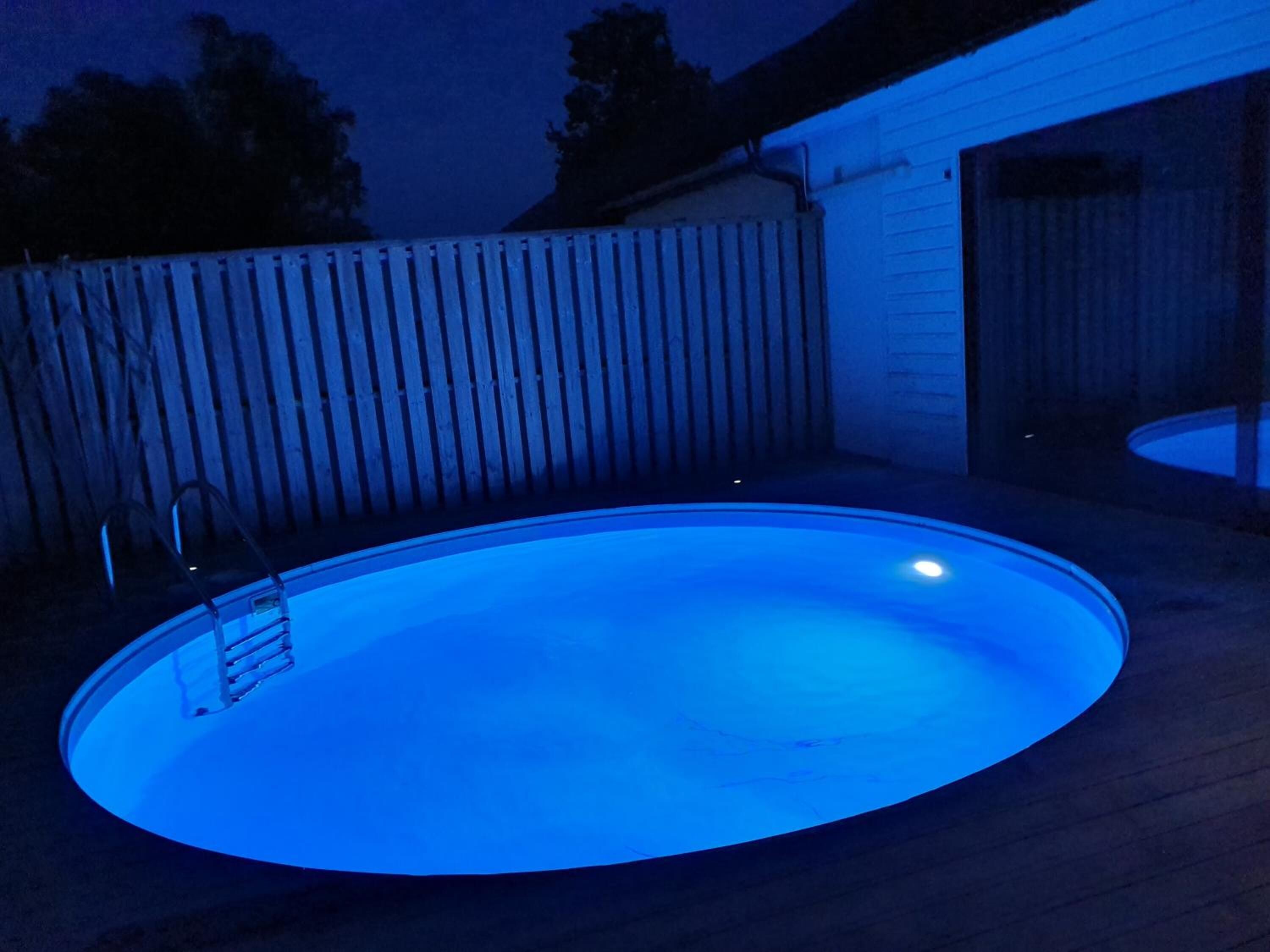 Una piscina con cubierta de madera y escalera de metal.