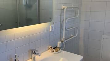 A bathroom with a white sink, a mirror, a towel rack, and a small stool.