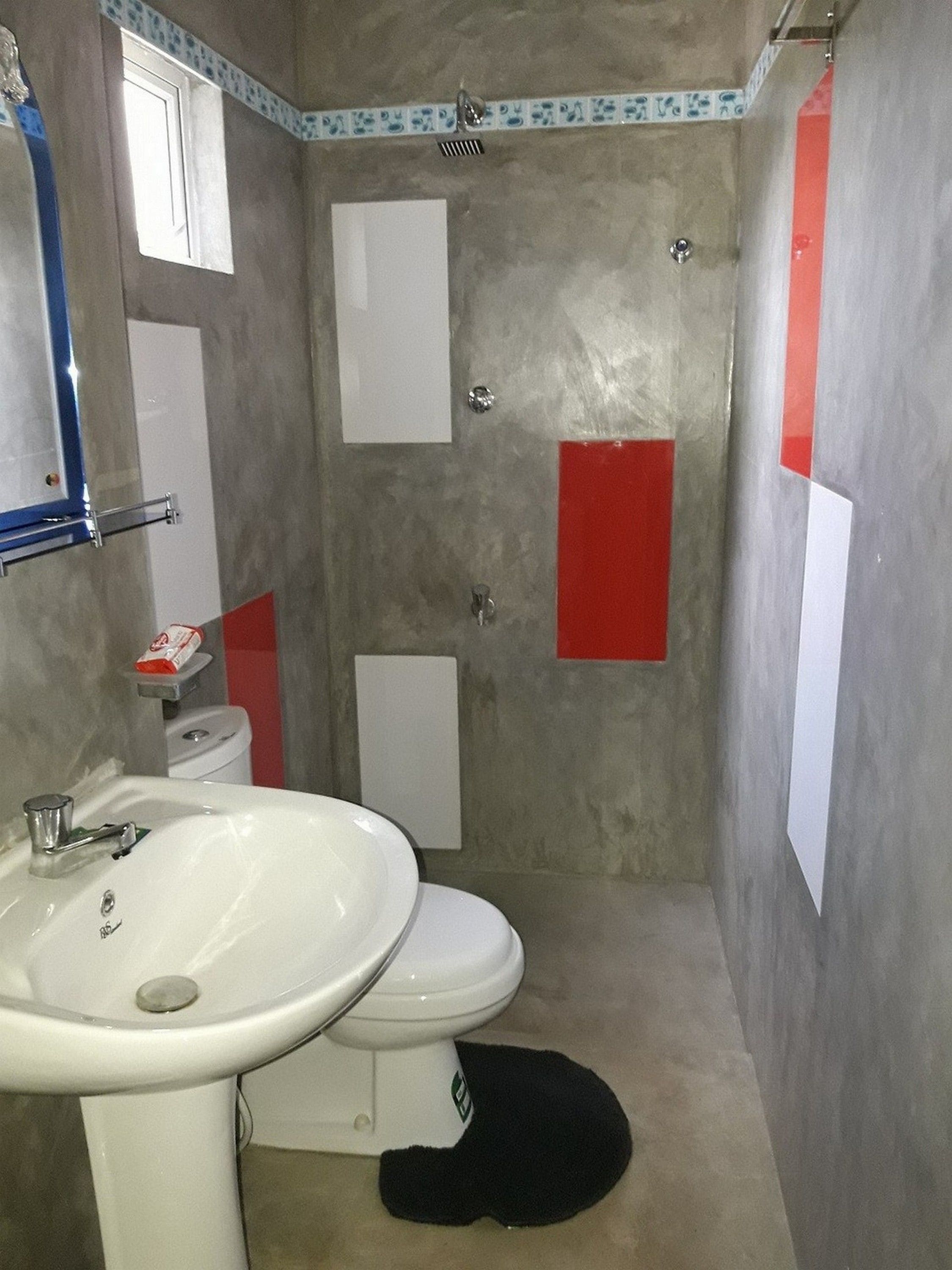 Un baño con lavamanos blanco, inodoro y zona de ducha.