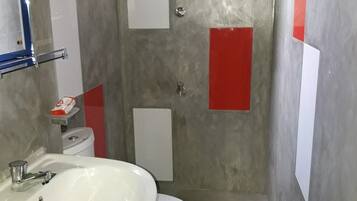 Un baño con lavamanos blanco, inodoro y zona de ducha.
