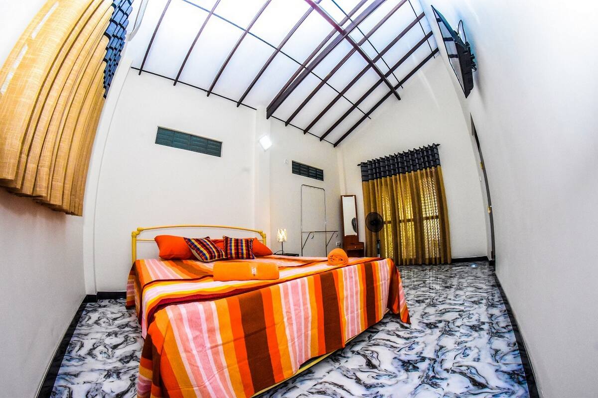 A room with a bed, a skylight, and a patterned floor.