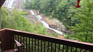 Une terrasse en bois offrant une vue sur une cascade et la forêt environnante.
