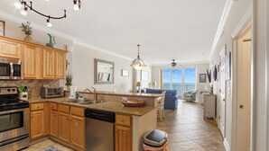 A spacious kitchen with wooden cabinets, stainless steel appliances, and a large island. - Tropic Winds 1504 - Amazing beachfront condo! Beach chairs included! (Panama City Beach)