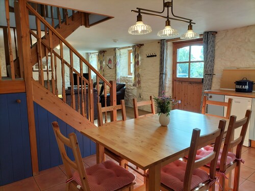 A cosy former horse stable with stone walls and old beams throughout