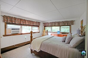 Cozy retreat with a double bed, bedside table, and lamp, set against a traditional backdrop with a painting and a chair.