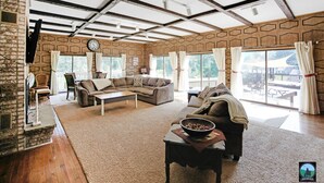 Een ruime woonkamer met een stenen openhaard, een grote hoekbank en een eethoek.