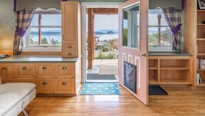 Una habitación con piso de madera, una cama, un escritorio, una ventana con cortinas y vistas al exterior.