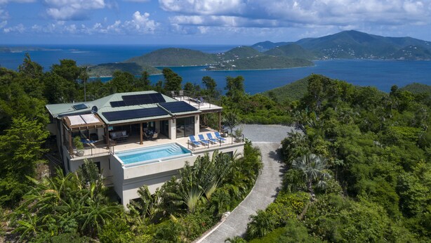 Una casa moderna con piscina, rodeada de vegetación exuberante y vistas al mar.
