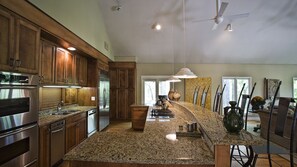 Uma cozinha moderna com bancadas de granito, eletrodomésticos de aço inoxidável, armários de madeira e uma ilha grande.
