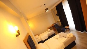 Una habitación de hotel con dos camas, un escritorio, una silla y una mesita.
