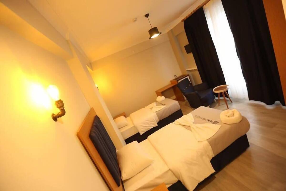A hotel room with two beds, a desk, a chair, and a small table.