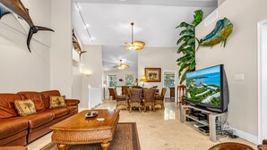 A spacious living room with a brown leather sofa, a wooden coffee table, and a large flat-screen TV. - Tropical Escape at Mariner’s Club  2BR Key Largo Condo w/ Pools & Marina (Key Largo)