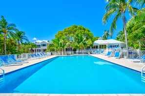Una piscina con sillas azules y palmeras.