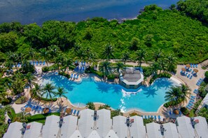An aerial view of a resort with a central swimming pool, surrounded by palm trees and beach chairs. - Tropical Escape at Mariner’s Club  2BR Key Largo Condo w/ Pools & Marina (Key Largo)